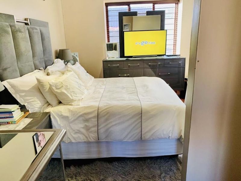 A well-lit bedroom featuring a large window with fitted blinds, providing a comfortable and functional sleeping space.