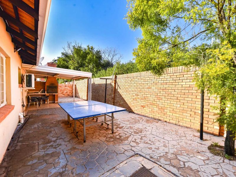 Outdoor covered patio area featuring a built-in brick braai, paved flooring, and enclosed by a perimeter brick wall.
