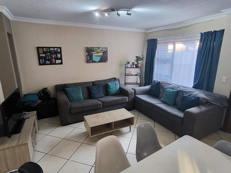 A comfortable living room featuring tiled flooring, coving, and ceiling-mounted track lighting, providing a functional and well-lit space for relaxation.