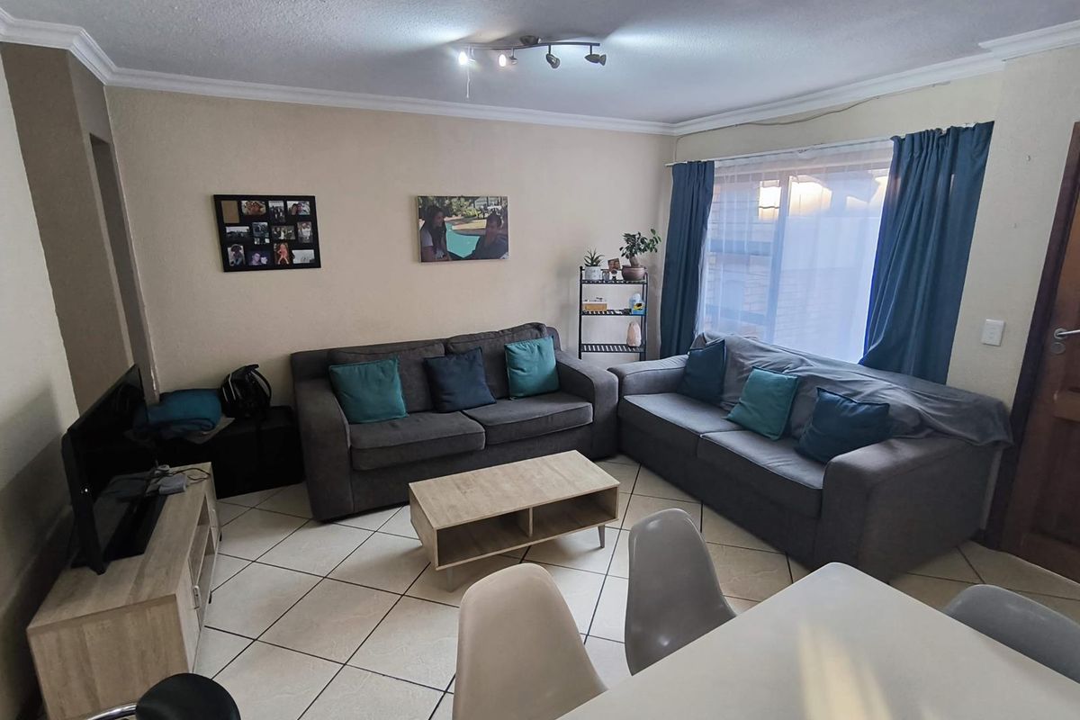 A comfortable living room featuring tiled flooring, coving, and ceiling-mounted track lighting, providing a functional and well-lit space for relaxation.