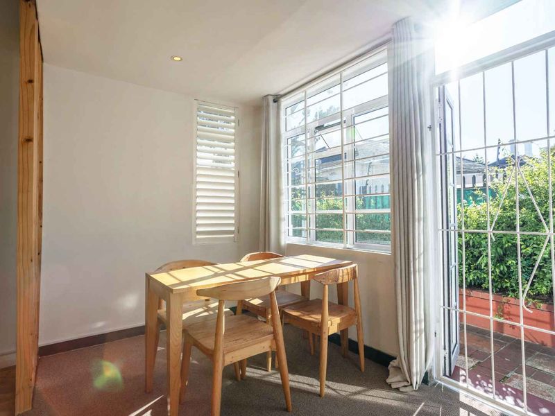 Bright dining area featuring large windows with security bars, plantation shutters, and direct access to an outdoor patio space.