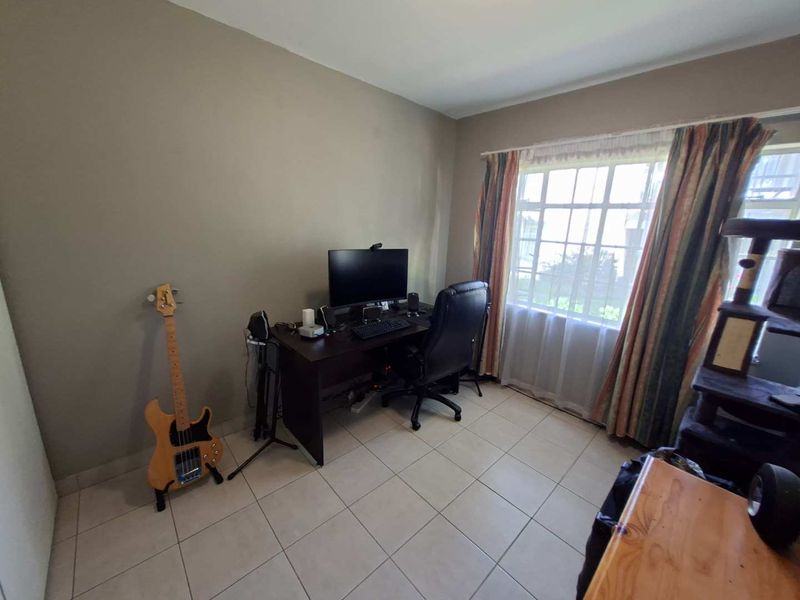 A functional bedroom featuring neutral wall tones, tiled flooring, and a large window that provides natural light.