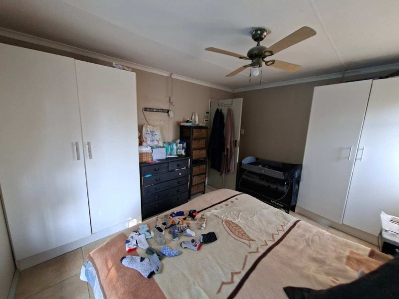 A bedroom featuring built-in cupboards, a ceiling fan, and tiled flooring.