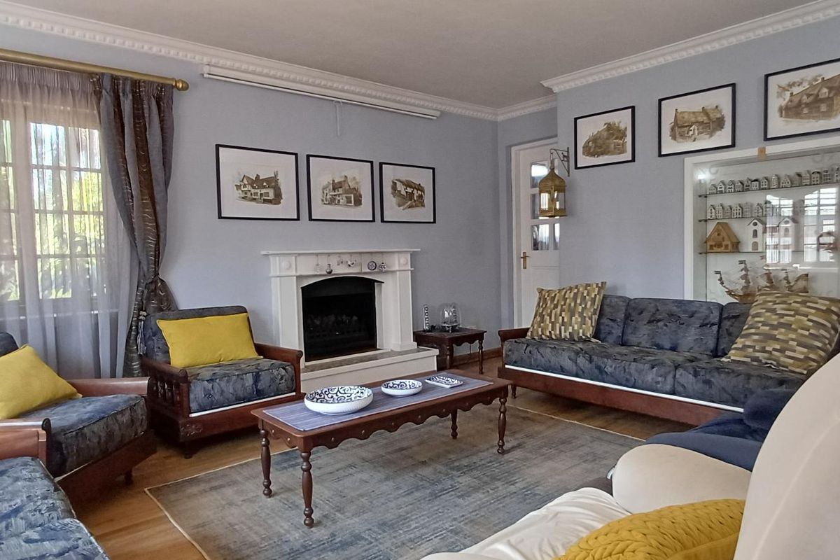 A comfortable living room featuring a classic fireplace with a mantelpiece, crown molding, and a built-in display cabinet, finished with hardwood flooring.