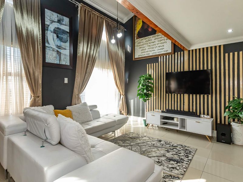 A modern living room featuring a sloped ceiling with an exposed timber beam, tiled flooring, and a decorative slatted timber wall feature.