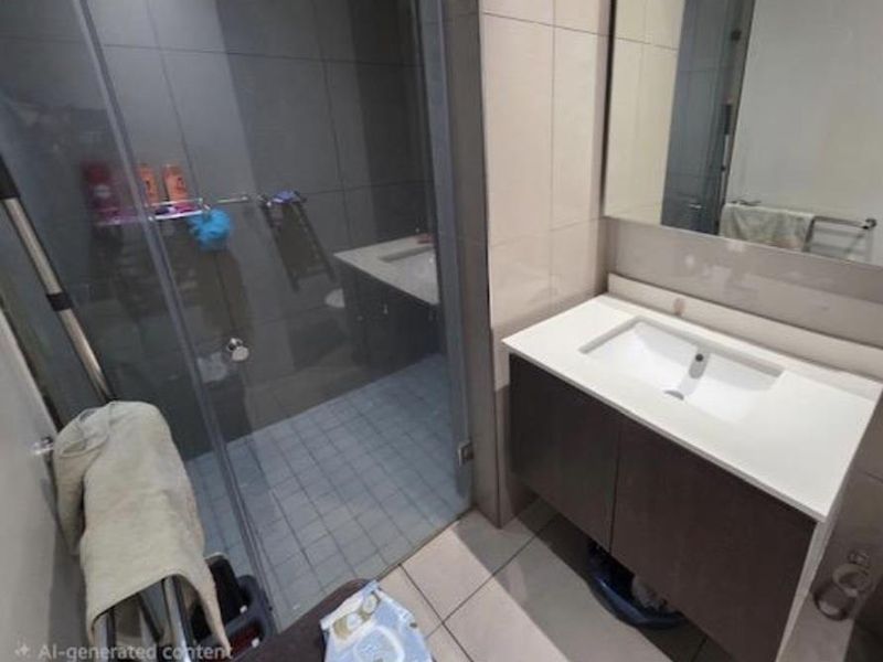 Modern bathroom featuring a vanity with integrated basin, wall-mounted mirror, and a glass-enclosed shower with tiled finishes.