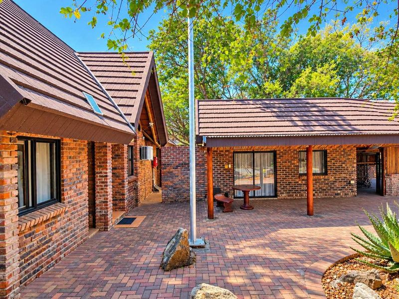 A well-maintained face brick exterior featuring a spacious paved courtyard, covered patio area, and classic tiled roofing, ideal for outdoor business or leisure use.