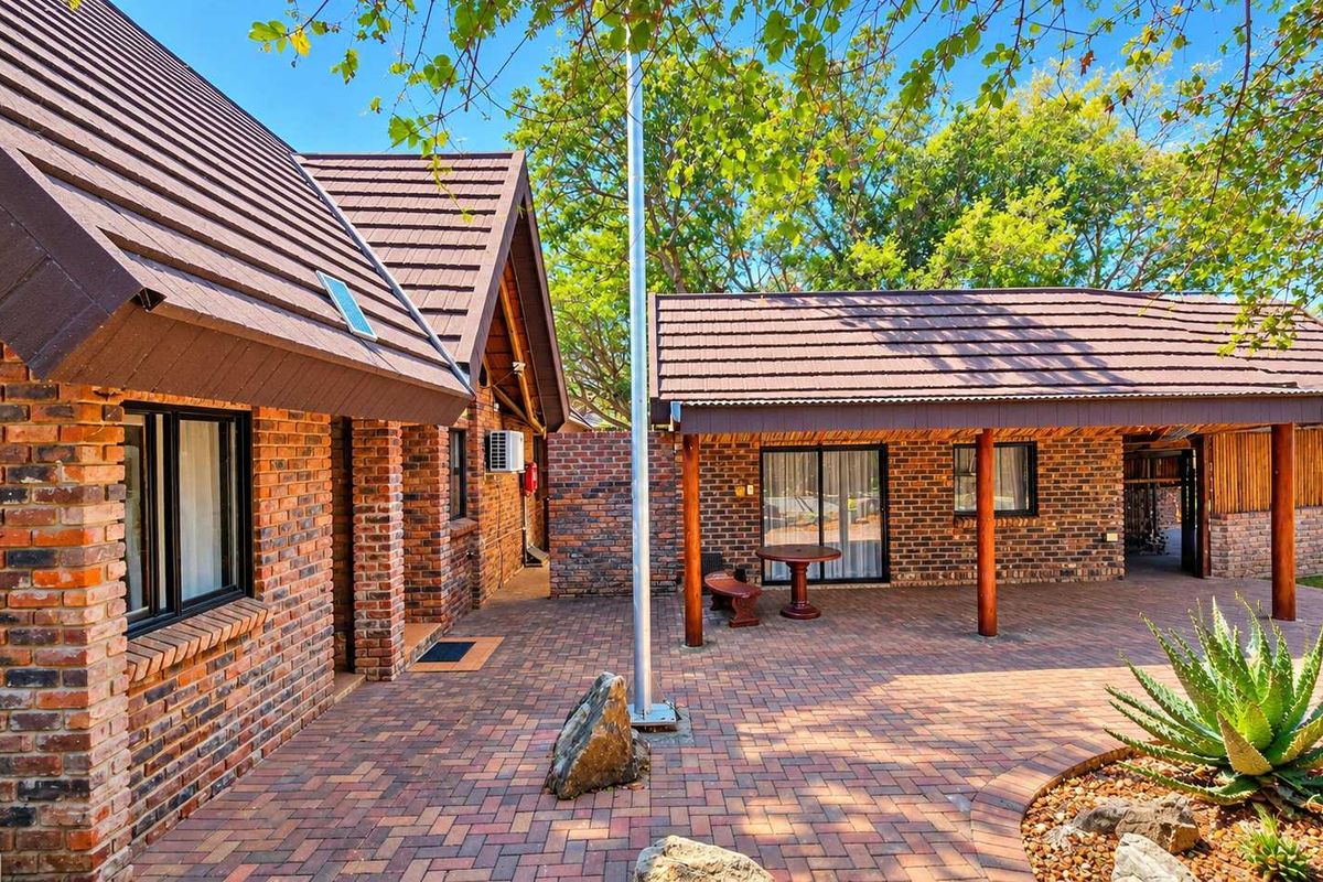 A well-maintained face brick exterior featuring a spacious paved courtyard, covered patio area, and classic tiled roofing, ideal for outdoor business or leisure use.