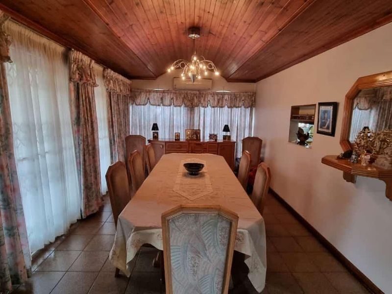 Formal dining room featuring a warm timber-clad ceiling, ceramic floor tiles, and a wall-mounted air conditioning unit for climate control.