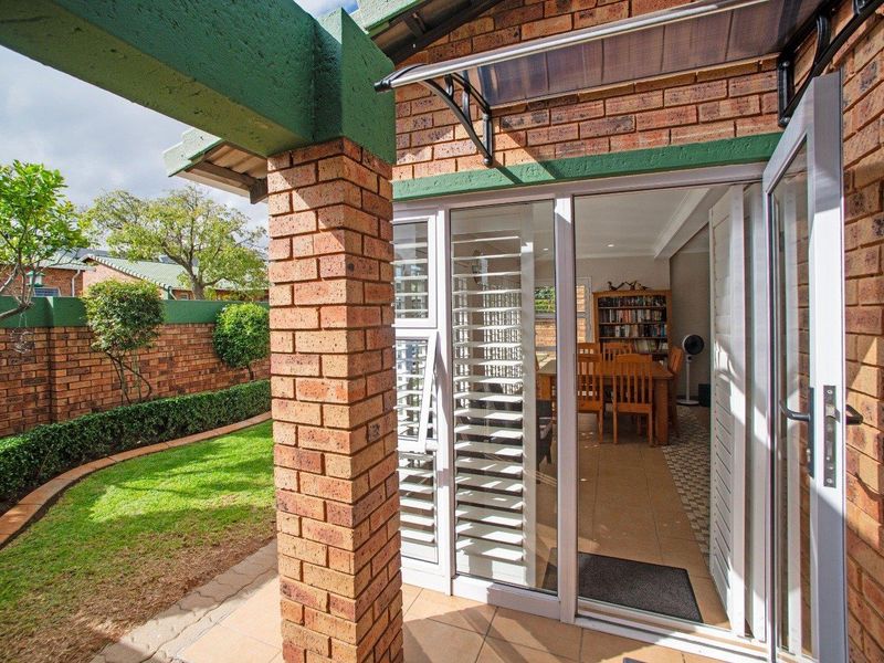 A covered patio area featuring brick pillars and tiled flooring, providing seamless access to the interior living space and overlooking a private garden.