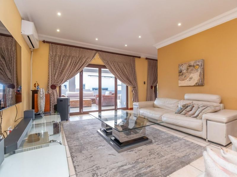 Spacious living room featuring tiled flooring, recessed downlighting, and large sliding glass doors providing seamless access to the outdoor patio area.