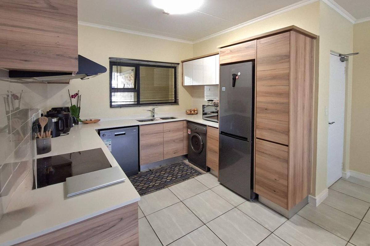 Modern kitchen featuring wood-grain cabinetry, stone countertops, integrated appliances, and tiled flooring, offering a clean and functional workspace.