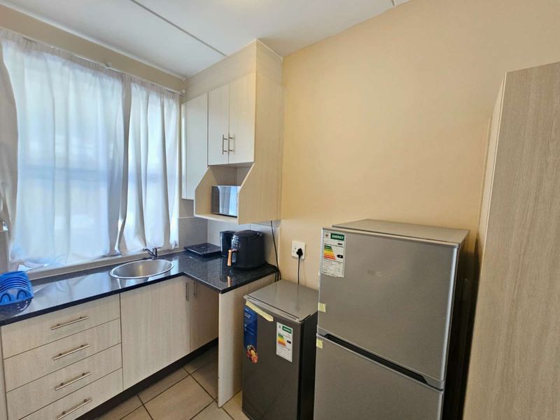 Compact kitchen featuring light wood-finish cabinetry, dark granite countertops, and a stainless steel sink, providing a functional and efficient workspace.