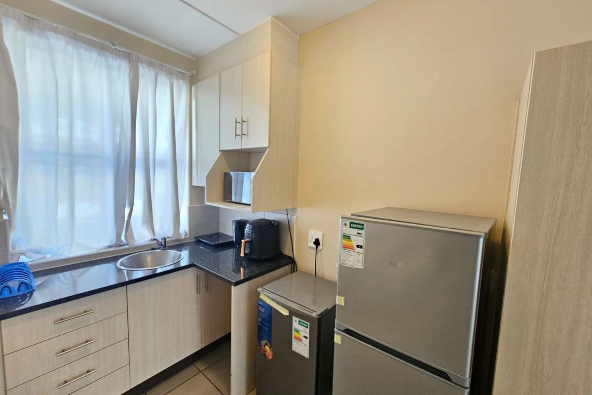 Compact kitchen featuring light wood-finish cabinetry, dark granite countertops, and a stainless steel sink, providing a functional and efficient workspace.