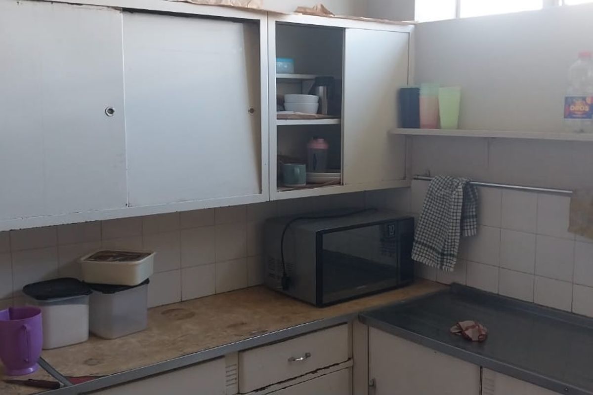 A functional kitchen area featuring built-in cabinetry, a stainless steel sink, and tiled splashbacks, offering a practical layout for daily meal preparation.