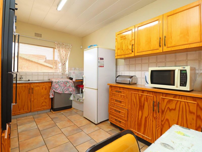 A functional kitchen featuring traditional wooden cabinetry, tiled flooring, and a tiled backsplash, offering a classic layout with ample storage space.