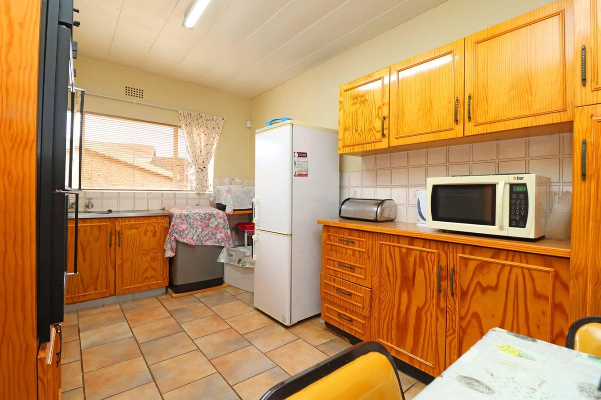 A functional kitchen featuring traditional wooden cabinetry, tiled flooring, and a tiled backsplash, offering a classic layout with ample storage space.