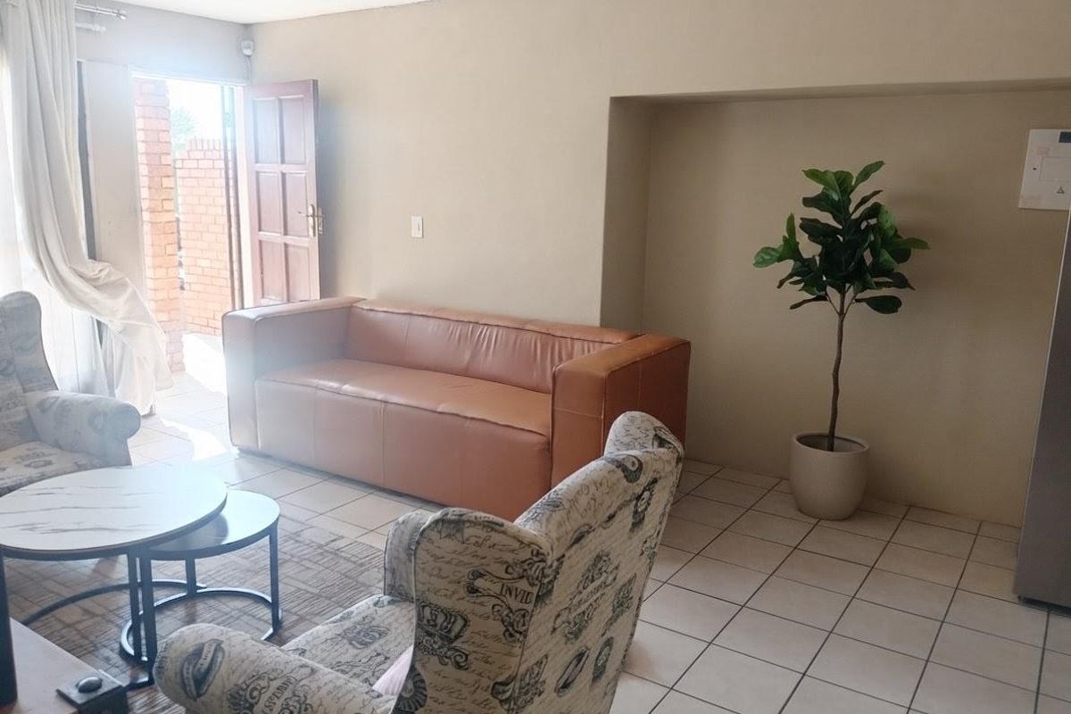 A living room area featuring tiled flooring and a recessed wall niche, with direct access to an outdoor patio area.