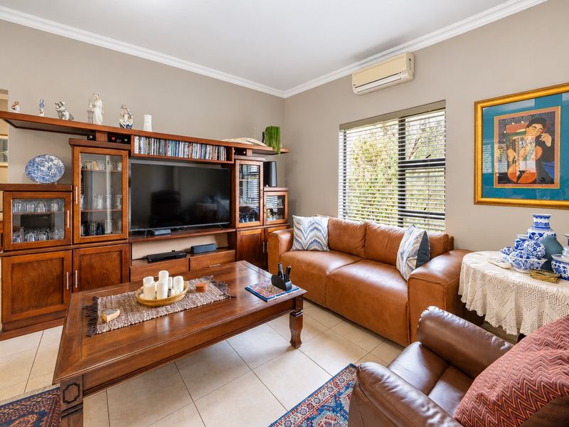 A comfortable living room featuring tiled flooring, crown molding, and a wall-mounted split-system air conditioner.