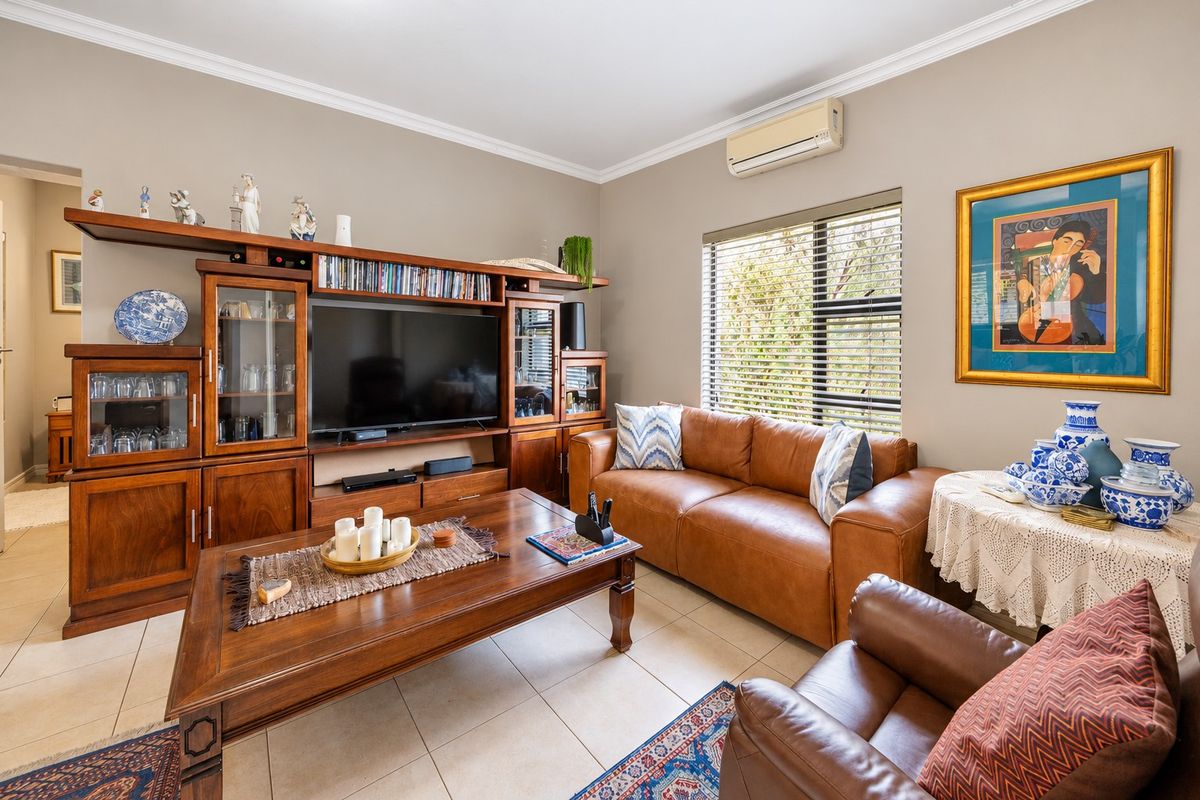 A comfortable living room featuring tiled flooring, crown molding, and a wall-mounted split-system air conditioner.