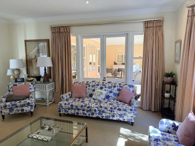 A comfortable living room featuring carpet flooring, recessed downlights, and double glass doors providing natural light and access to the outdoor area.