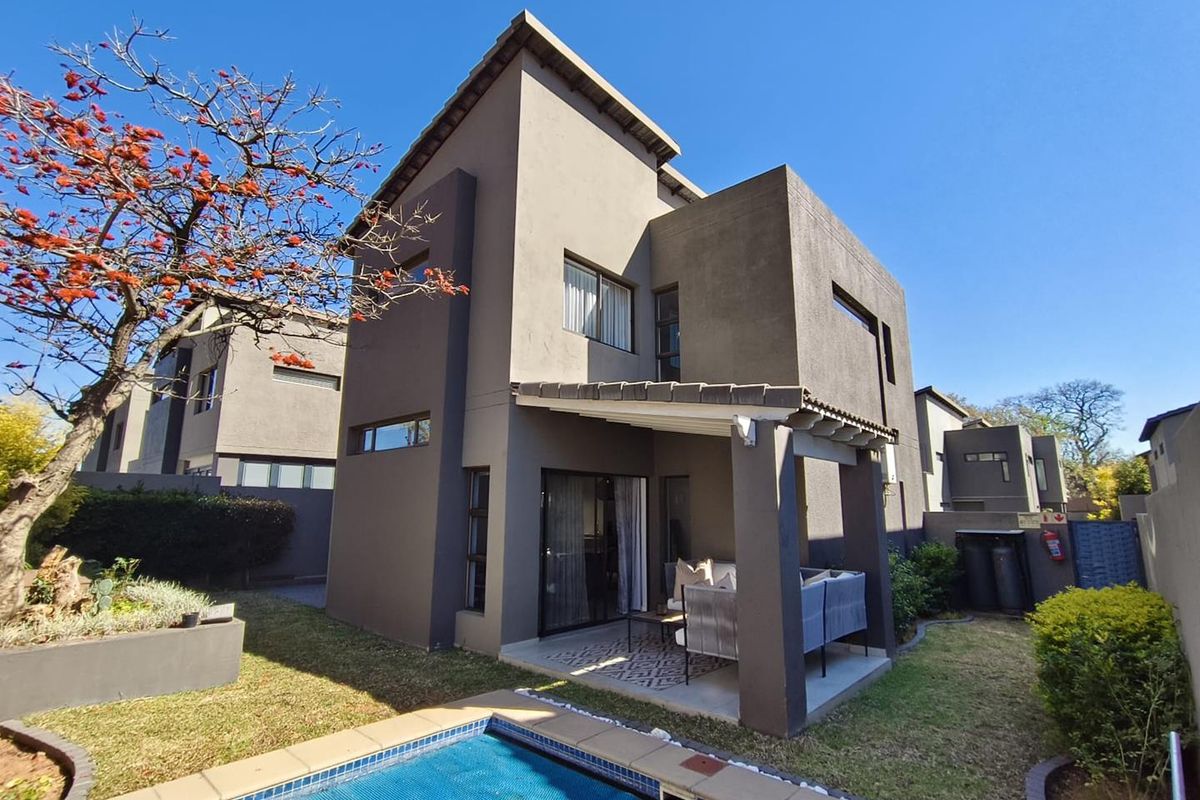 Rear view of a modern double-story house featuring a covered patio, private swimming pool, and landscaped garden area.