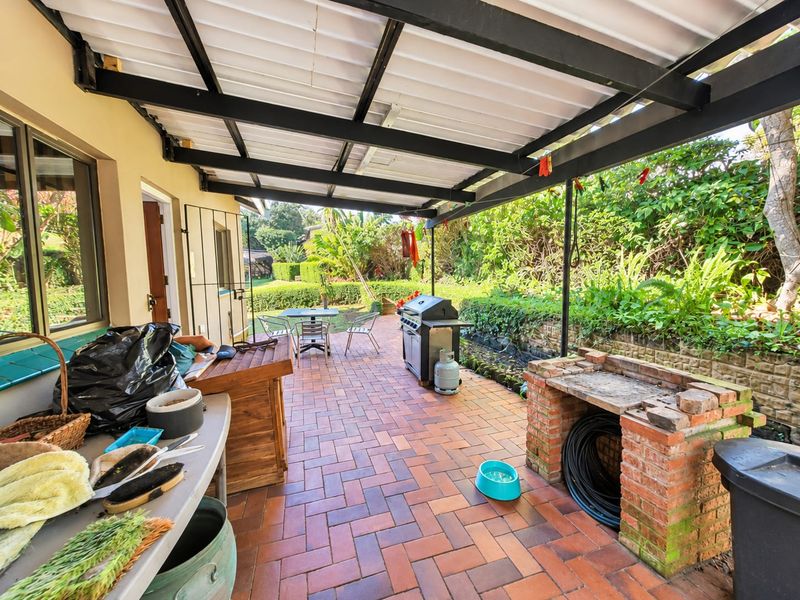 A covered outdoor patio area featuring brick paving and a built-in brick braai, providing a functional space for outdoor entertaining and relaxation.