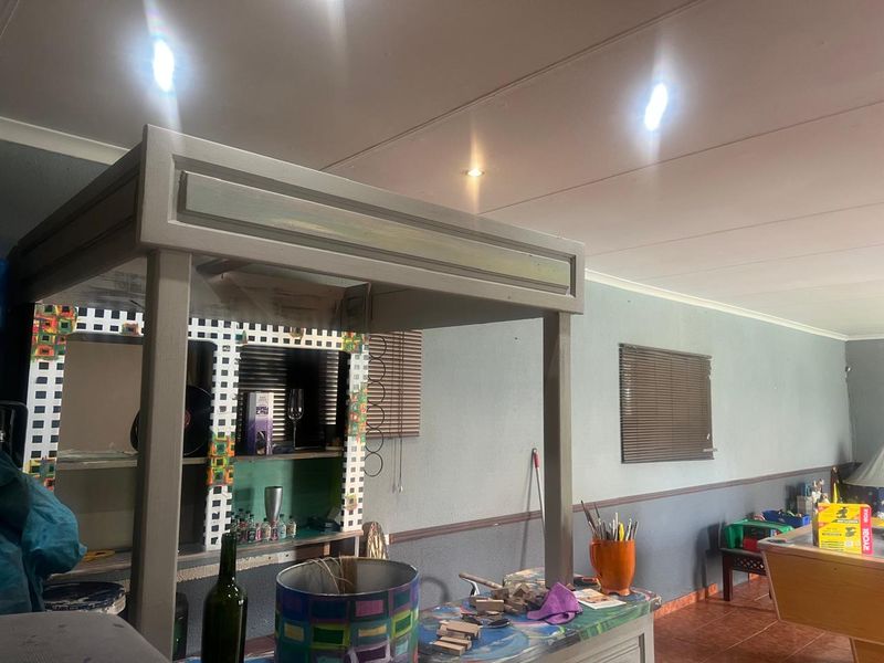 A dedicated bar area featuring a built-in counter, recessed ceiling lighting, and tiled flooring, offering potential for a modern entertainment space update.