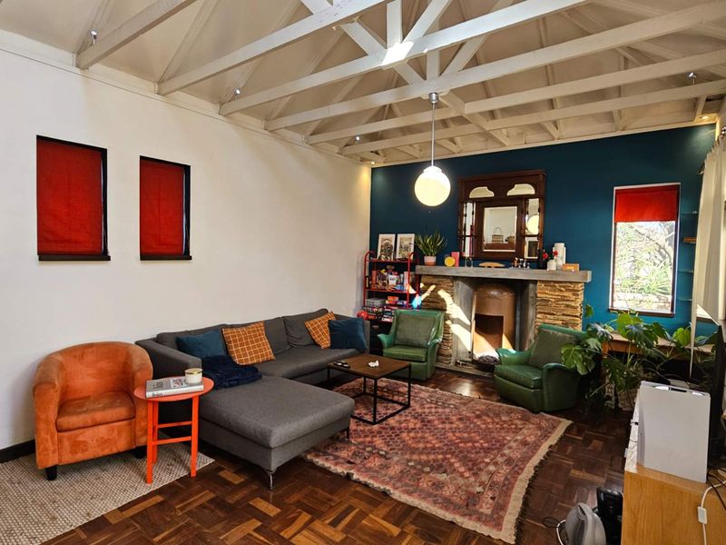 Spacious living room featuring a vaulted ceiling with exposed timber trusses, a stone fireplace, and classic parquet flooring.