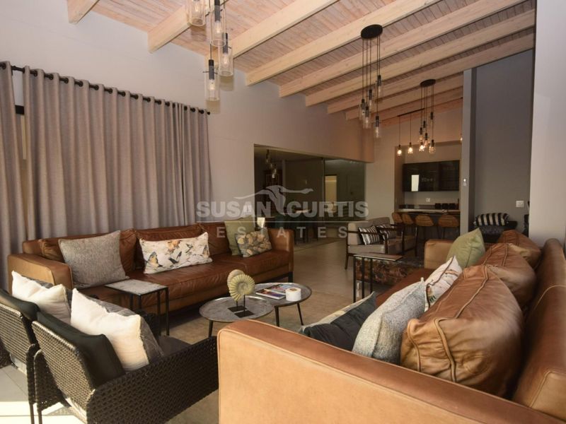 Spacious open-plan living area featuring exposed timber ceiling beams, modern pendant lighting, and a seamless transition to the kitchen space.