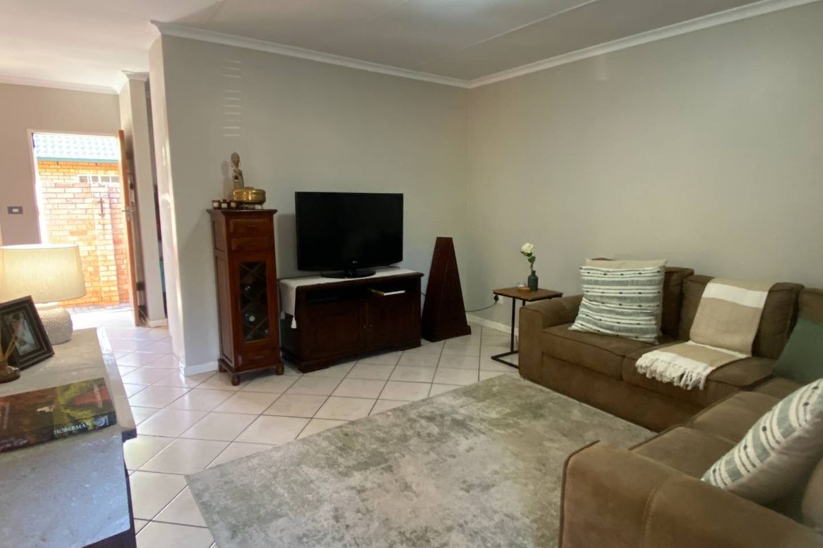 A comfortable living room featuring tiled flooring and a neutral color palette, with direct access to an exterior entrance area.