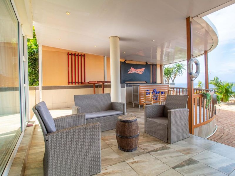 Spacious covered patio featuring a built-in bar area, tiled flooring, and scenic outdoor views, perfect for entertaining.