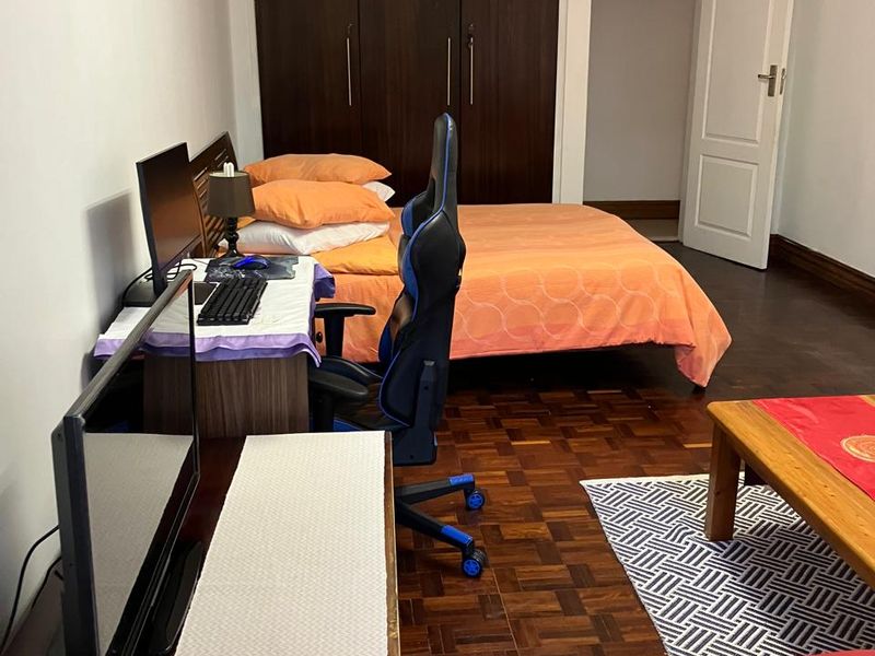 A bedroom featuring dark wood built-in cupboards and classic parquet flooring, offering a functional space with traditional finishes.