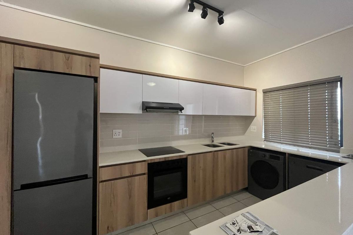 Modern kitchen featuring sleek wood-tone and white cabinetry, quartz countertops, integrated appliances, and contemporary track lighting.