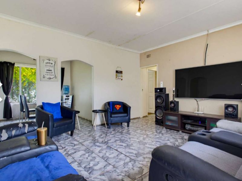 Living room featuring tiled flooring and arched doorways, showing signs of ceiling water damage and wear.