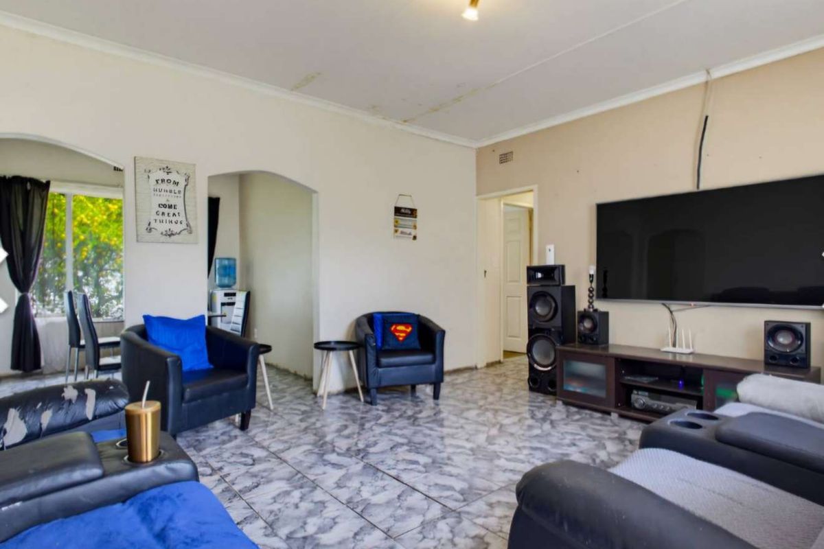 Living room featuring tiled flooring and arched doorways, showing signs of ceiling water damage and wear.