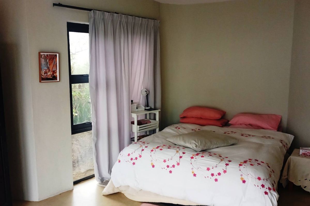 A functional bedroom featuring a large window with curtain tracks and neutral wall finishes.