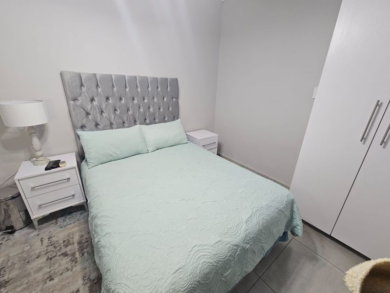 A well-maintained bedroom featuring neutral wall tones, tiled flooring, and a functional built-in wardrobe.