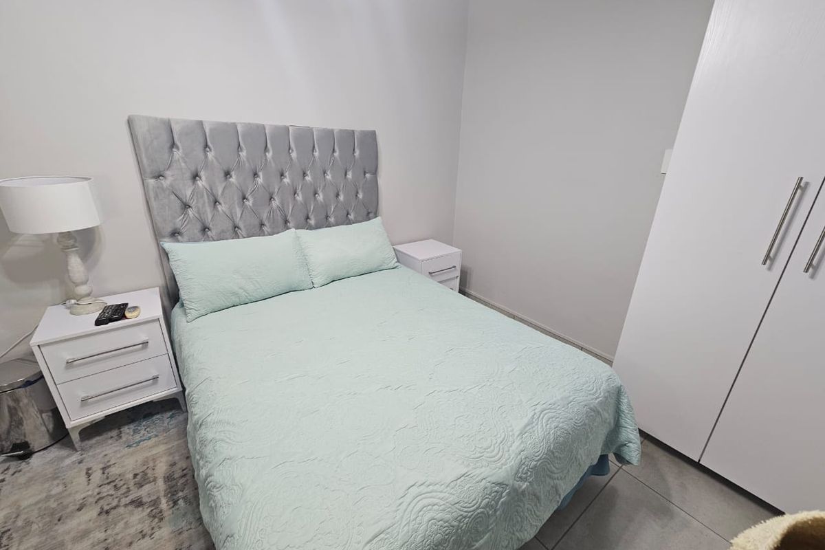 A well-maintained bedroom featuring neutral wall tones, tiled flooring, and a functional built-in wardrobe.