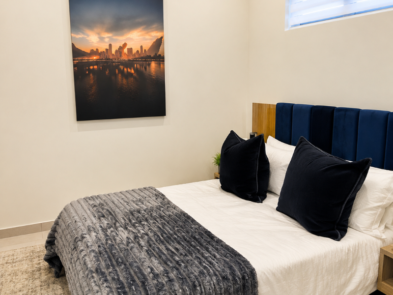 A well-maintained bedroom featuring neutral walls, tiled flooring, recessed lighting, and a horizontal window blind.