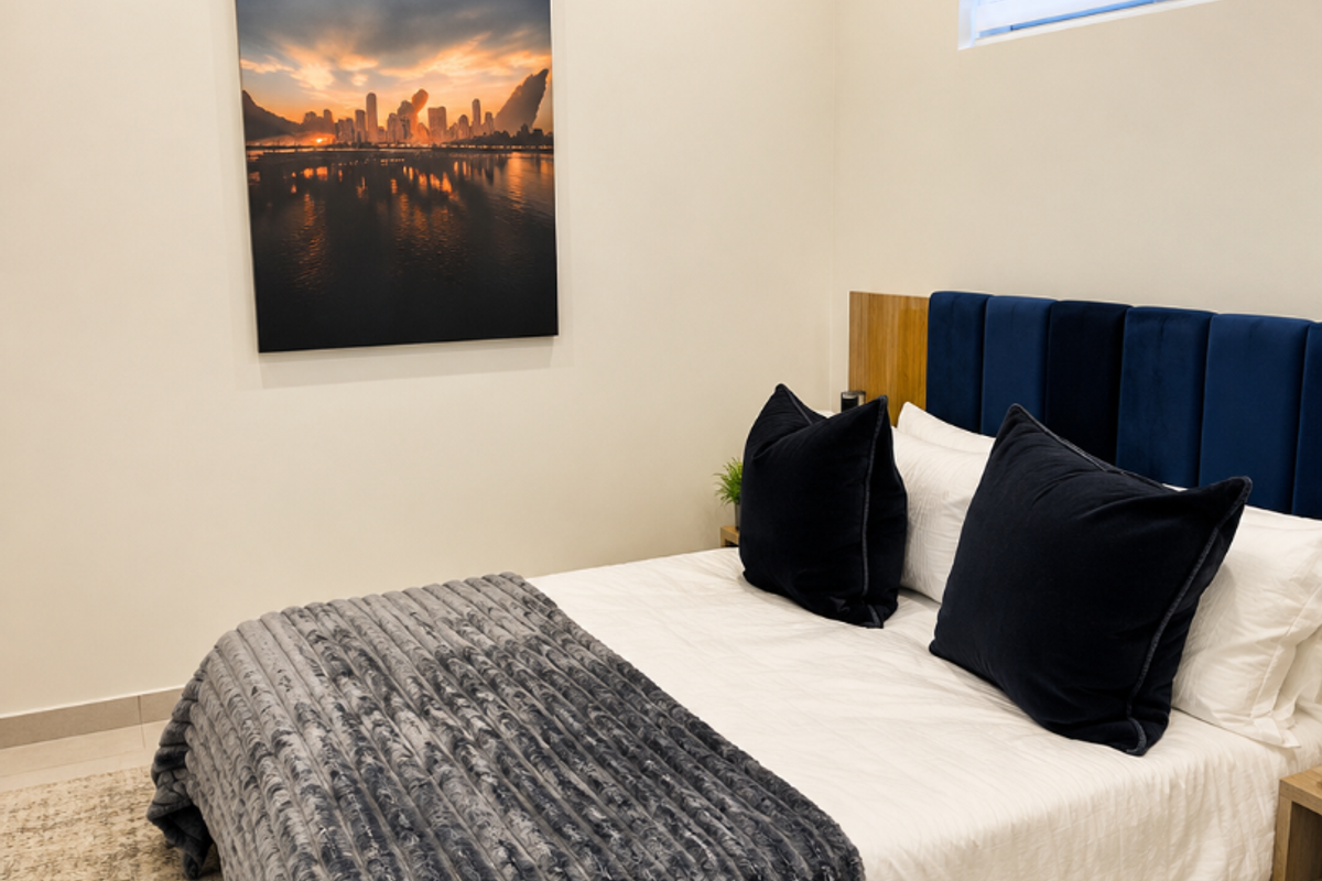 A well-maintained bedroom featuring neutral walls, tiled flooring, recessed lighting, and a horizontal window blind.