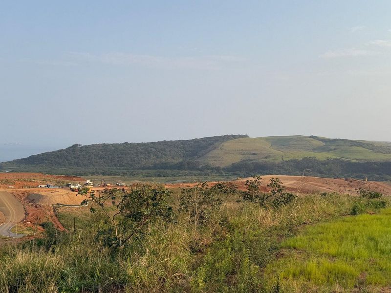 A wide-angle view of an undeveloped residential land parcel featuring ongoing earthworks and scenic coastal landscape views.