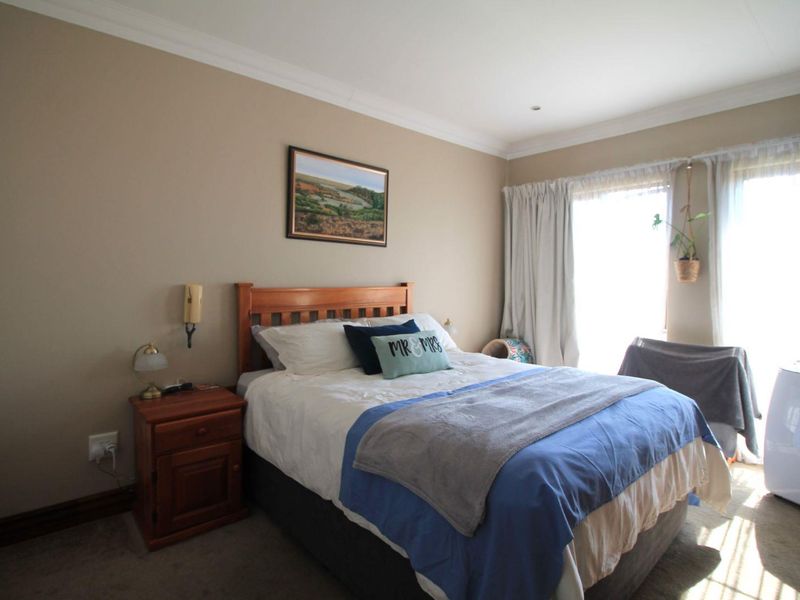 A well-lit bedroom featuring neutral wall tones, crown molding, and large windows with curtain tracks, providing a comfortable and functional living space.