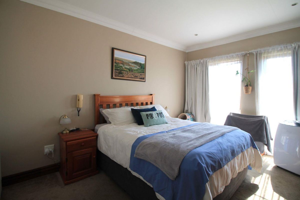 A well-lit bedroom featuring neutral wall tones, crown molding, and large windows with curtain tracks, providing a comfortable and functional living space.