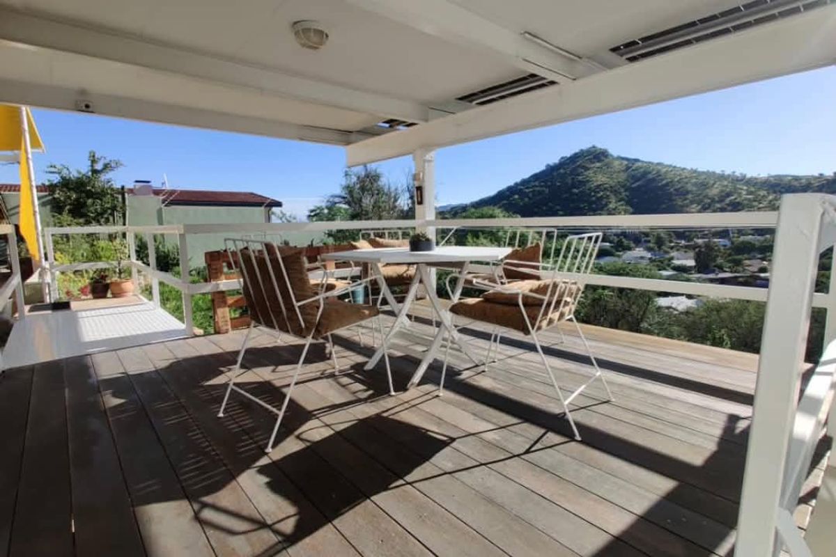 Covered outdoor deck featuring timber decking, white railing, and panoramic mountain views, providing an ideal space for outdoor relaxation.