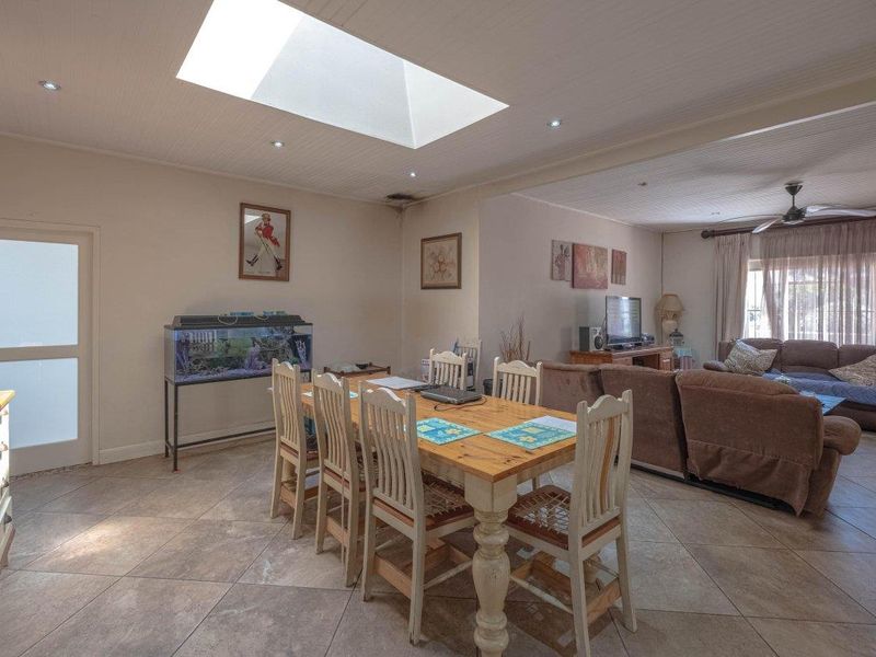 Spacious open-plan living and dining area featuring a large skylight, tiled flooring, and a tongue and groove ceiling with recessed lighting.