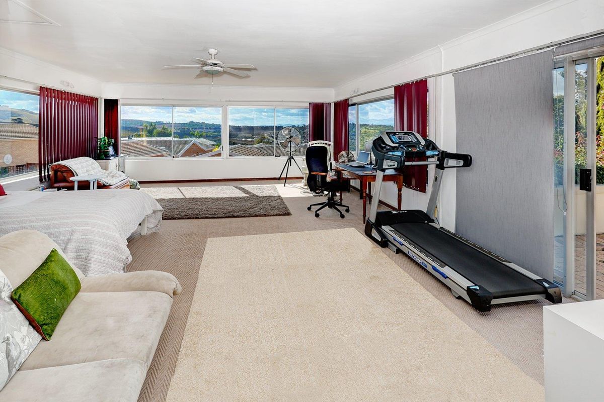 Spacious living area featuring large windows with panoramic views, ceiling fan, and sliding door access to the exterior.