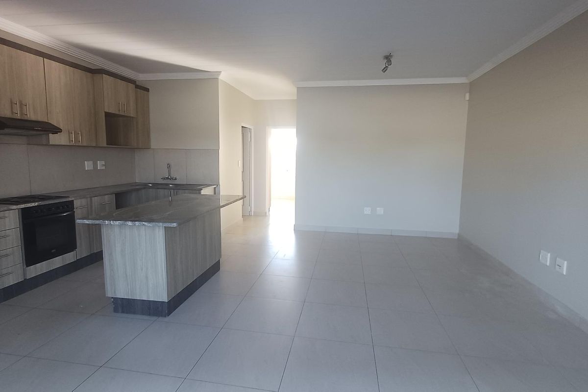Spacious open-plan living area featuring a modern kitchen with built-in cabinetry, an island, and tiled flooring throughout.