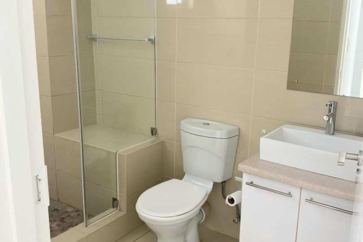 Modern bathroom featuring a glass-enclosed shower with a built-in bench, wall-mounted vanity with basin, and neutral floor-to-ceiling tiling.