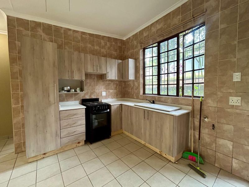 A functional kitchen featuring light wood-look cabinetry, tiled splashbacks, and tiled flooring. The space is ready for updates to modernize the finishes.